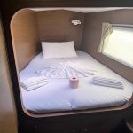 Cabine avant du catamaran Lagoon 380 avec lit double, hublots et rangements pour une croisière confortable aux Grenadines.