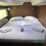 Cabine arrière du catamaran Lagoon 380 avec lit double, rangements et hublots offrant un confort idéal pour une croisière aux Grenadines.