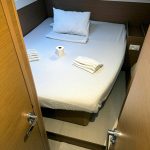 Cabine arrière du catamaran Excess 12 avec lit double, rangements et hublots panoramiques pour une croisière aux Grenadines.