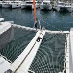 Trampoline avant du catamaran Excess 12 avec espace de détente offrant une vue panoramique sur les eaux turquoise des Grenadines.