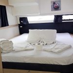 Cabine arrière du catamaran Fountaine Pajot Saba 50 avec lit double, rangements et vue sur les Grenadines pour une croisière confortable.
