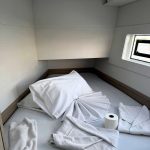 Cabine avant du catamaran Lagoon 40 avec lit double, hublots panoramiques et rangements pour une croisière confortable aux Grenadines.