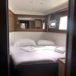 Cabine avant du catamaran Lagoon 450 avec lit double, hublots panoramiques et espace de rangement pour une croisière aux Grenadines.