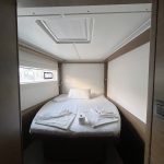 Cabine avant du catamaran Lagoon 46 avec lit double, hublots panoramiques et rangements pour une croisière aux Grenadines.