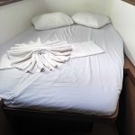 Cabine avant du catamaran Lagoon 50 avec lit double, hublots panoramiques et rangements pour une croisière aux Grenadines.